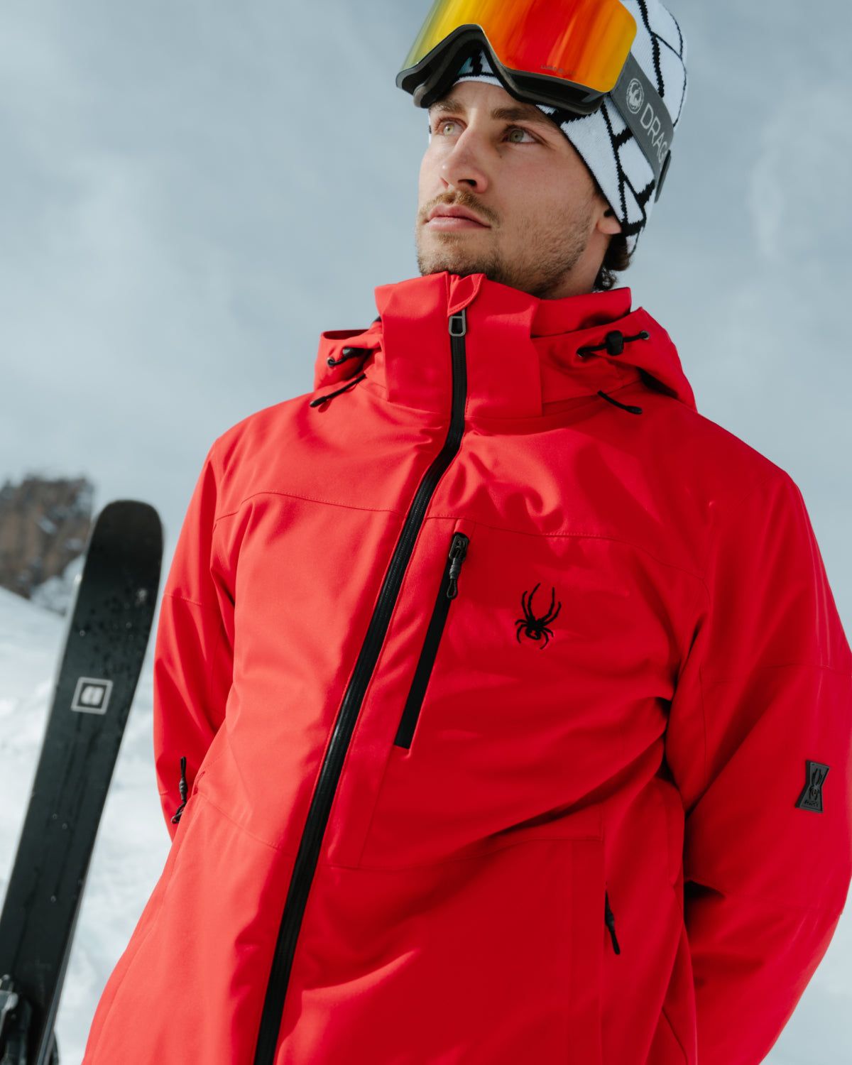Skier in a red Spyder jacket holding skis